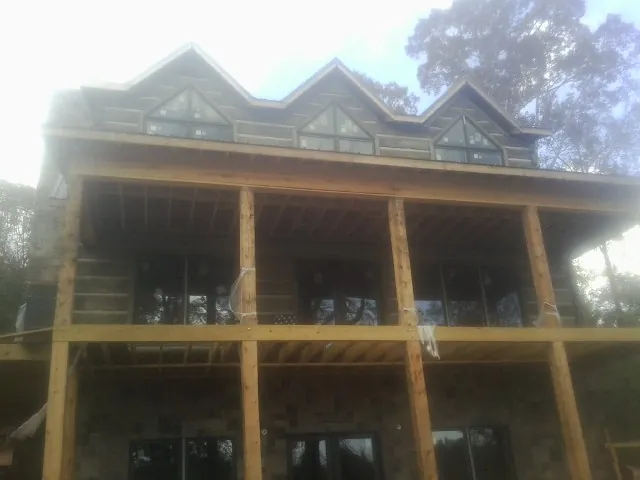 Dormers and porch framing on a large log home under construction — Roof Coating work by our crew in Sunburg