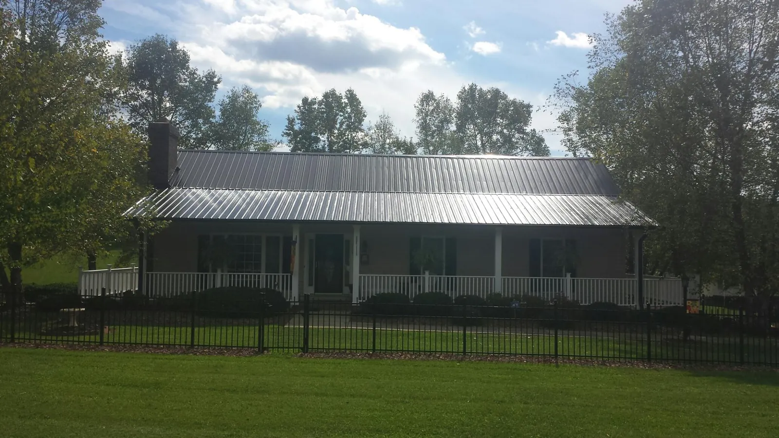 Gray metal roof on a brick ranch with a full width front porch — Gutter Guard Installation work by our crew in Sunburg