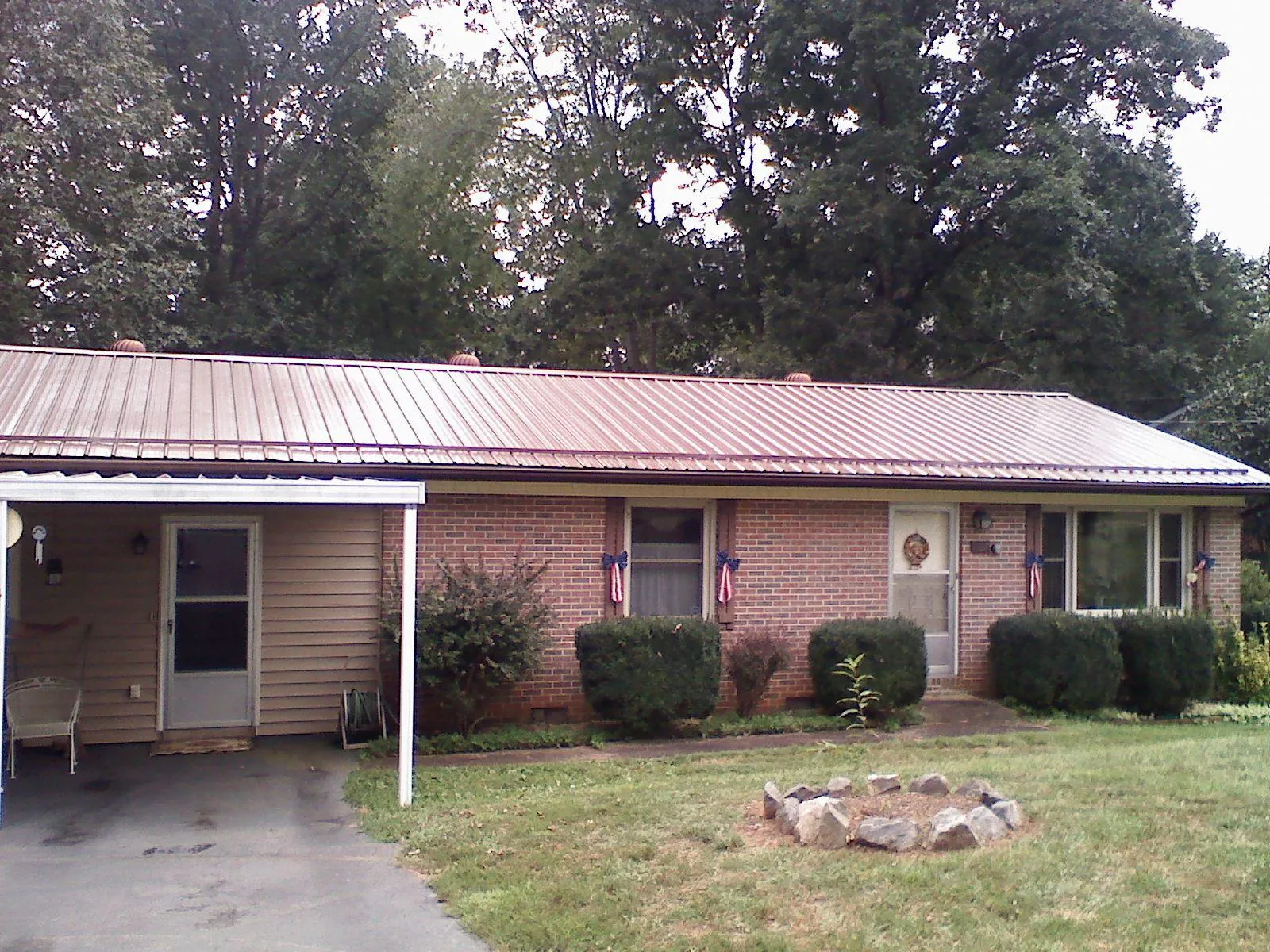 Bronze metal roof and carport on a brick ranch home — Roof Repair work by our crew in Sunburg
