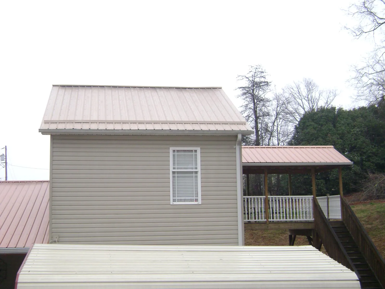 Tan metal roofs on a two story addition and attached porch, from a Roof Replacement job in Sunburg