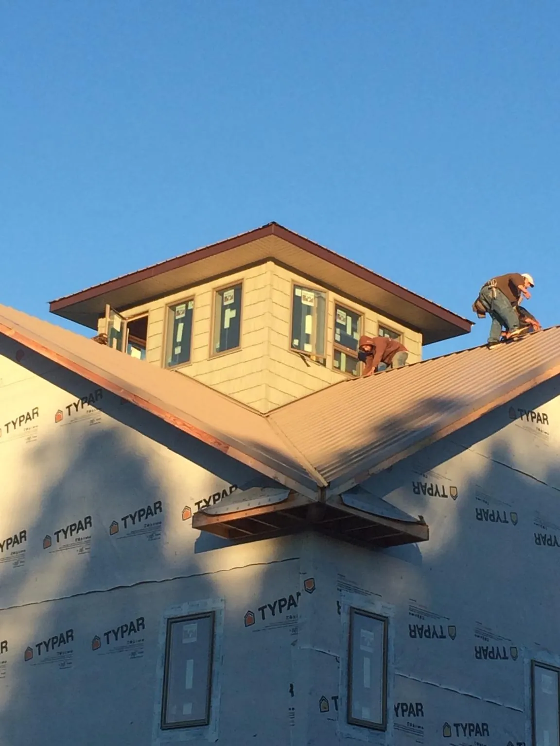 Roofers working around a rooftop cupola on a new metal roof at sunset — Roof Waterproofing in Sunburg by Roofing Brothers
